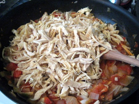 Adding shredded chicken to onions and tomatoes